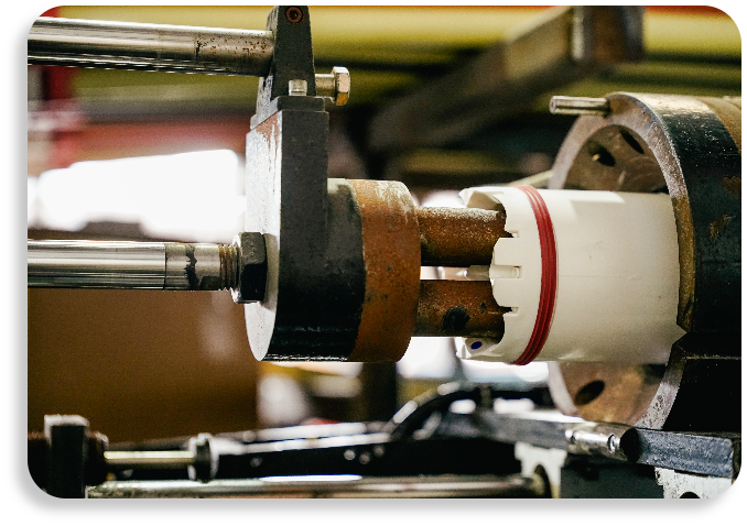 Industrial mechanical fabrication components aligning a specialized white pipeline sleeve on a factory line.