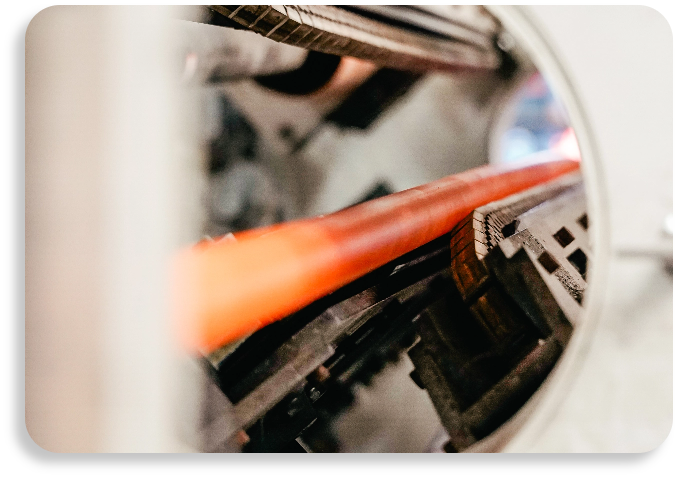 An orange HDPE pipeline passing through industrial manufacturing machinery during the extrusion phase.