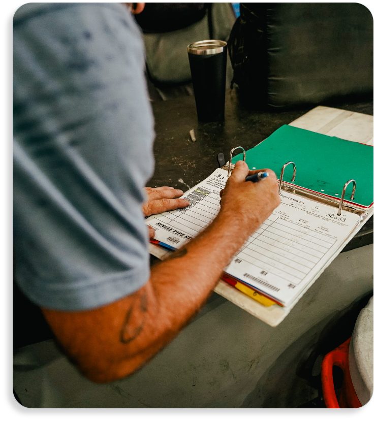 An administrative worker reviewing manufacturing and supply documentation inside a green binder on site.