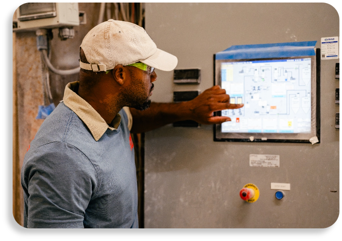 A factory technician operating an electronic process control screen on an industrial production line terminal