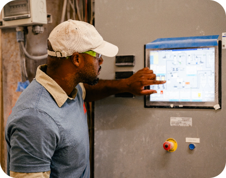 A manufacturing technician operating a digital control system panel on a factory line.